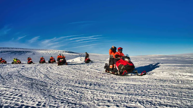 Row of snowmobiles under a clear blue sky on Langjökull glacier on a Langjökull snowmobile tour from Geysir, Iceland